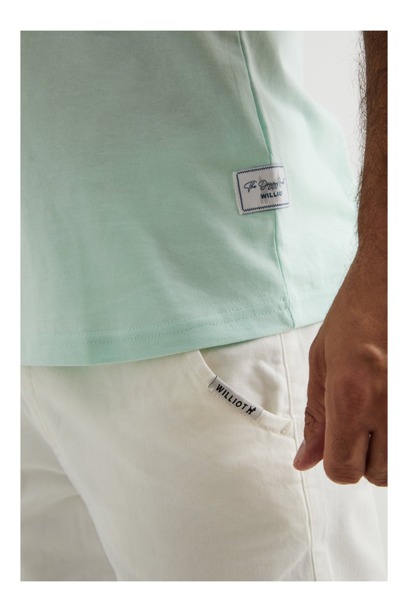  Camiseta turquesa con logo bordado en rojo tipo parche. Color y estilo para tu día a día. 