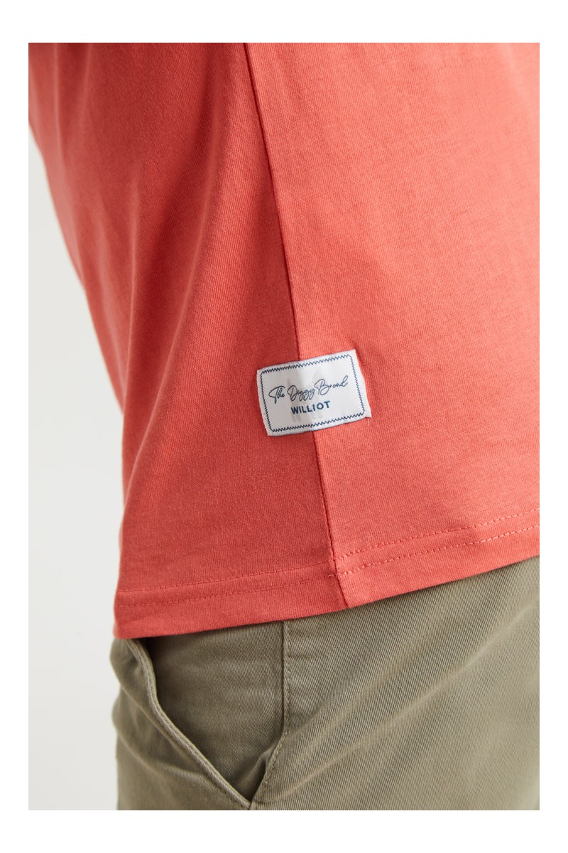 Camiseta coral con logo bordado en rojo tipo parche. Comodidad y estilo con un color vibrante.  2