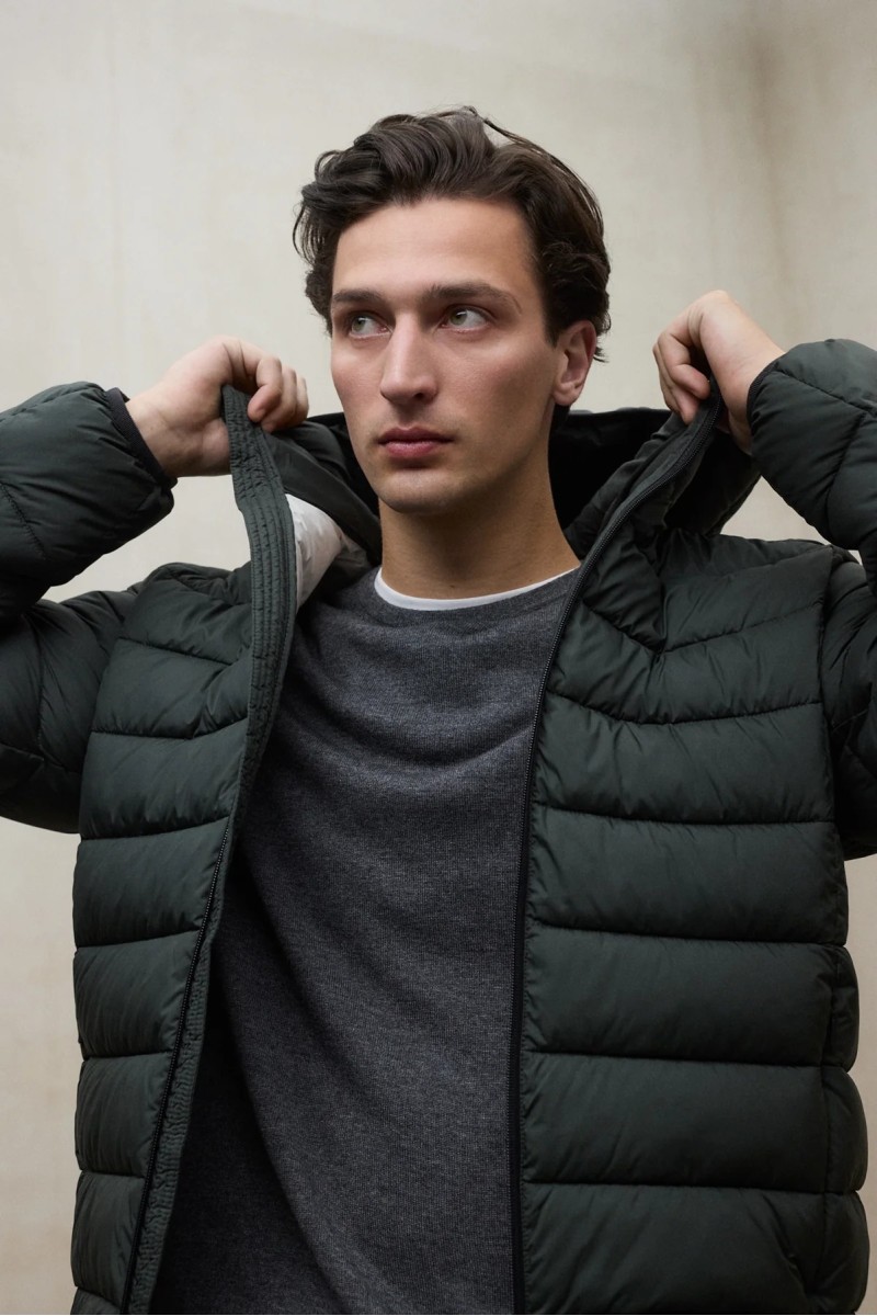  Chaqueta acolchada en tono Beetle, con capucha ajustable y diseño pensado para ofrecer abrigo ligero en ambientes urbanos. 