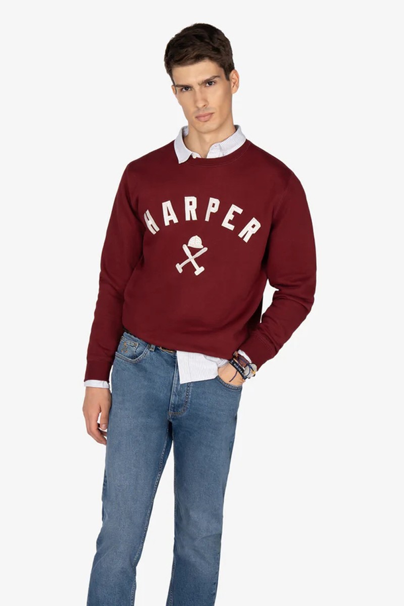  Sudadera estilo “college” en tono burdeos, con textura suave, cuello reforzado y diseño gráfico emblemático. 