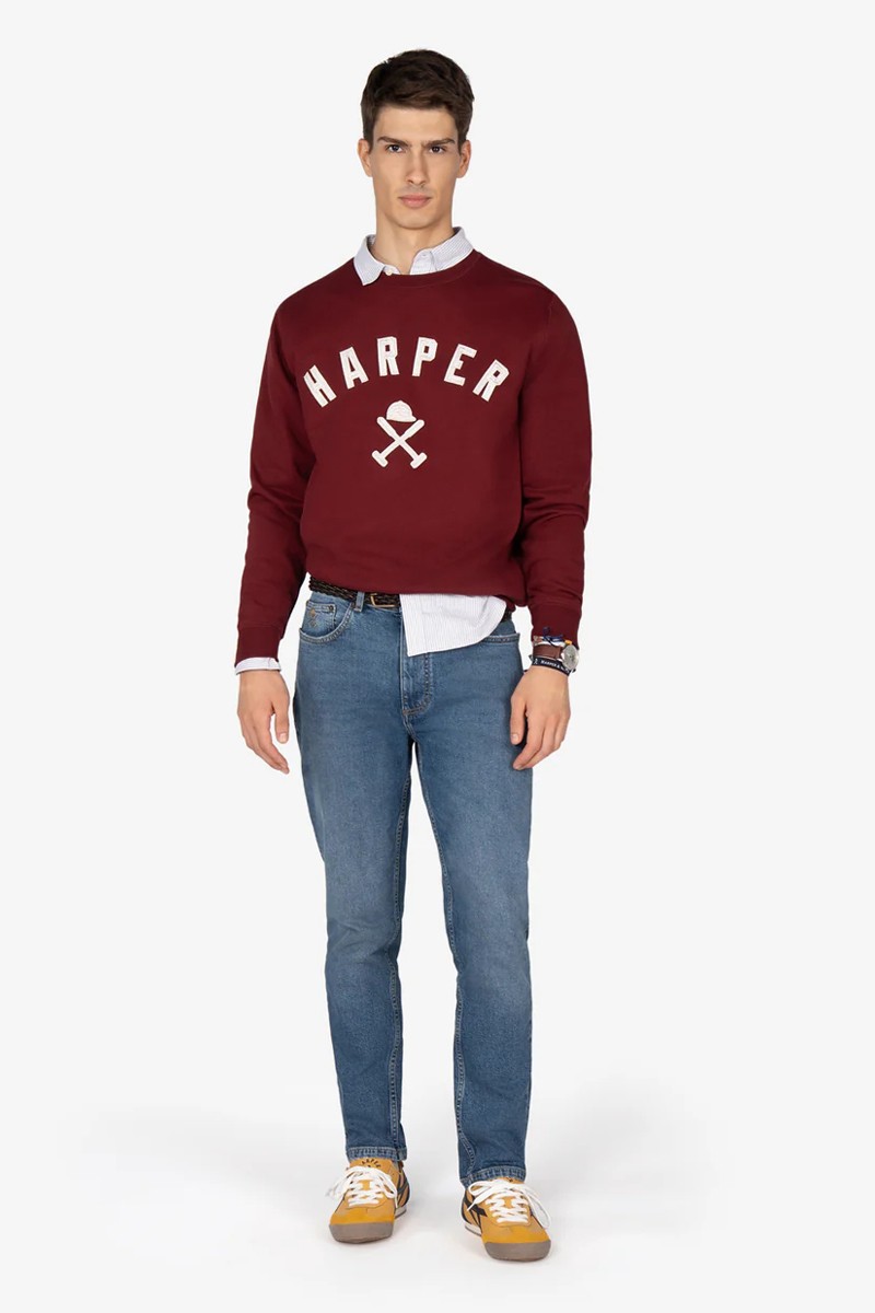 Sudadera estilo “college” en tono burdeos, con textura suave, cuello reforzado y diseño gráfico emblemático.