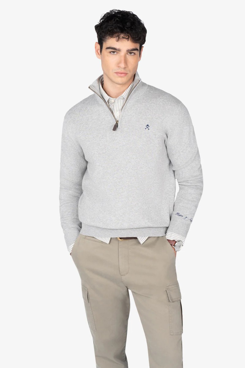Jersey de punto en algodón con cuello alto y media cremallera, logo discreto al frente y detalles acanalados.