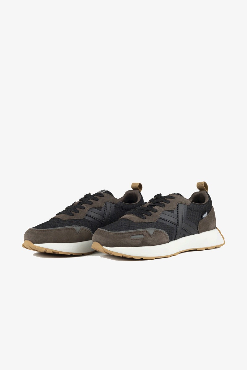  Zapatillas Munich de inspiración retro running que combinan elegancia deportiva y estética urbana. Su mezcla de negro, marrón oscuro, blanco y suela color caramelo crea un diseño atemporal y fácil de combinar. 
