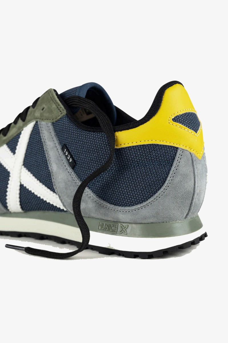  Zapatillas Munich de inspiración retro running que recuperan una silueta histórica de la marca. Su combinación de gris claro, azul petróleo y amarillo aporta un estilo deportivo y urbano con personalidad.  2
