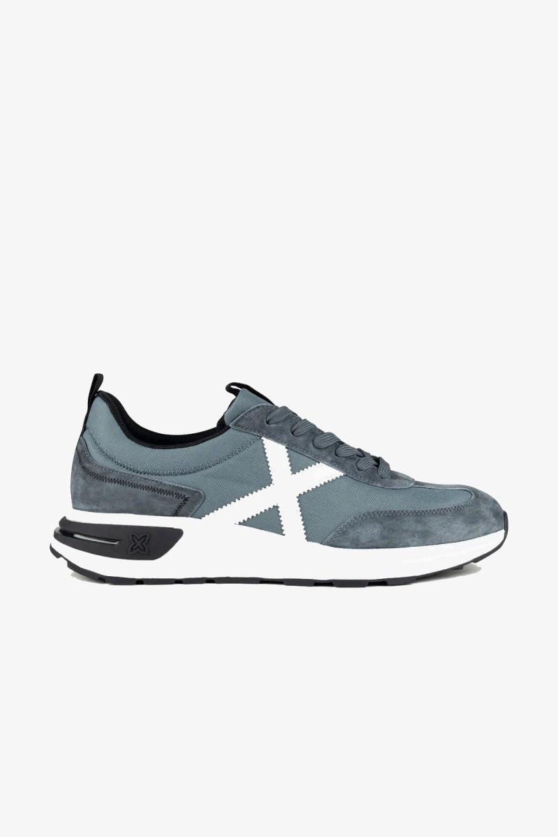  Zapatillas Munich de inspiración running de los años 80 con una estética urbana y casual. Su combinación de gris azulado y blanco aporta un estilo deportivo, sobrio y fácil de integrar en los looks diarios. 