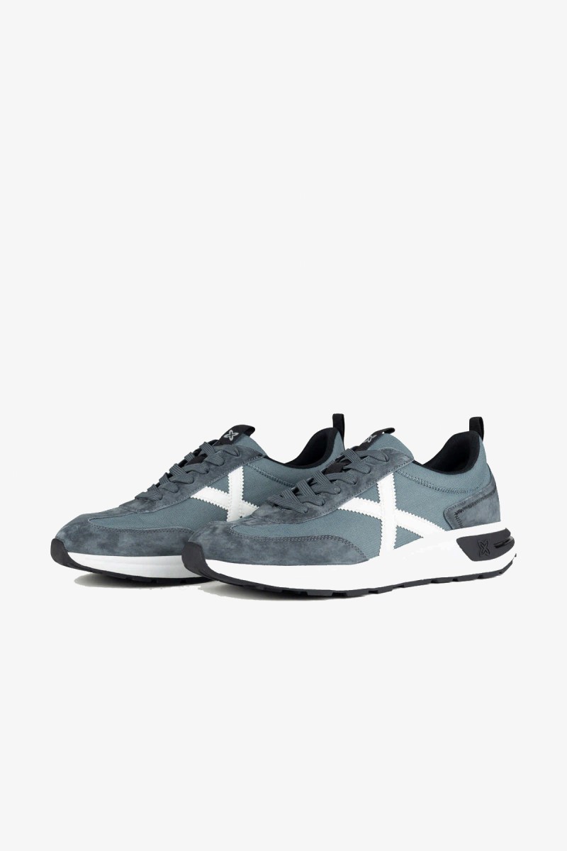  Zapatillas Munich de inspiración running de los años 80 con una estética urbana y casual. Su combinación de gris azulado y blanco aporta un estilo deportivo, sobrio y fácil de integrar en los looks diarios. 