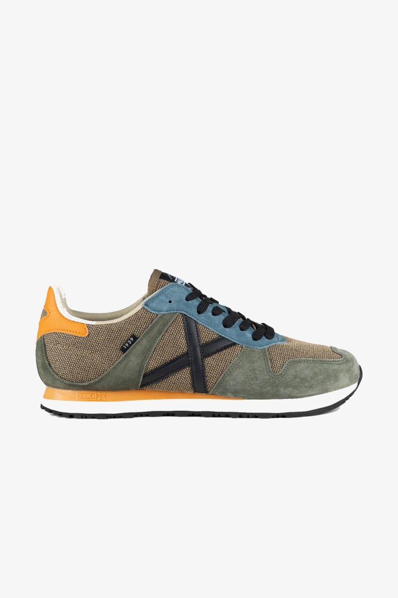  Zapatillas Munich de inspiración running de los años 80 con una estética urbana y casual. Su combinación de gris azulado y blanco aporta un estilo deportivo, sobrio y fácil de integrar en los looks diarios. 