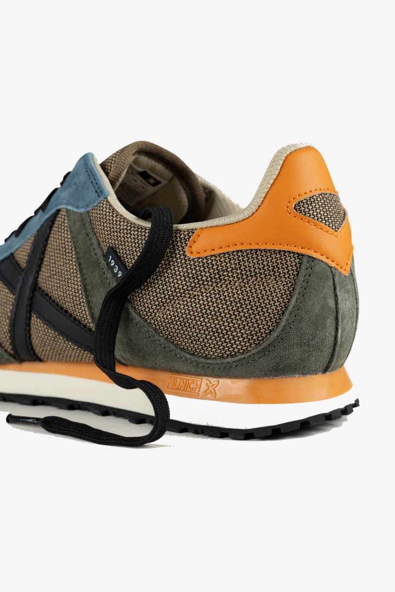  Zapatillas Munich de inspiración running de los años 80 con una estética urbana y casual. Su combinación de gris azulado y blanco aporta un estilo deportivo, sobrio y fácil de integrar en los looks diarios. 
