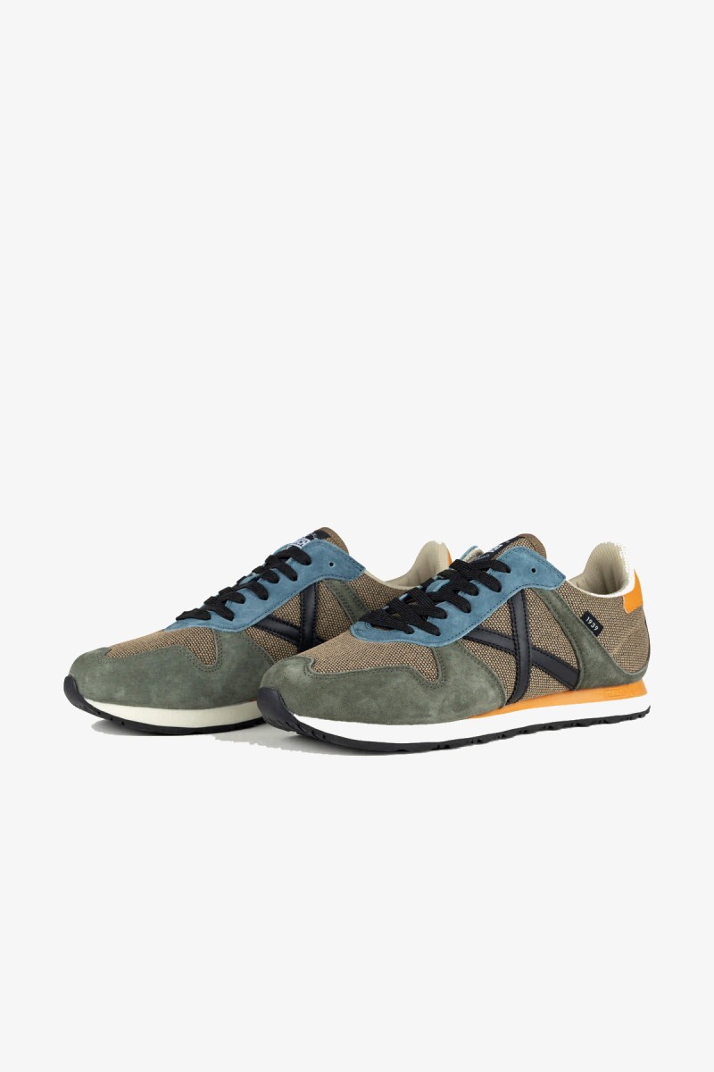  Zapatillas Munich de inspiración running de los años 80 con una estética urbana y casual. Su combinación de gris azulado y blanco aporta un estilo deportivo, sobrio y fácil de integrar en los looks diarios. 