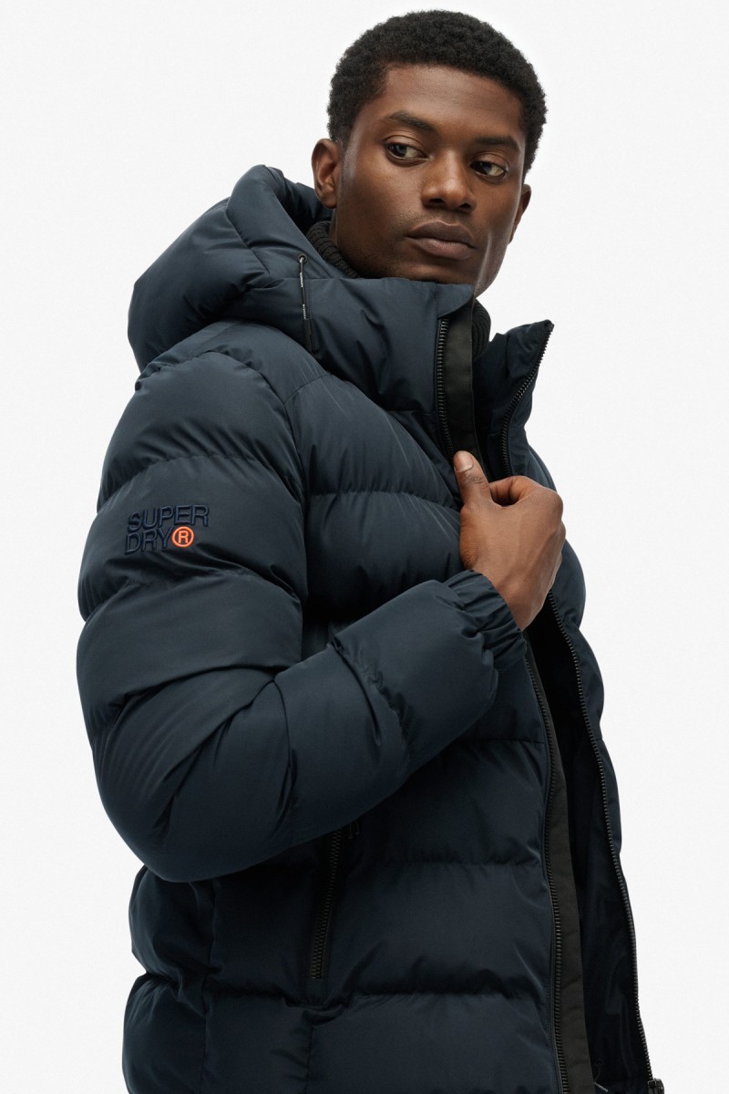  Cazadora acolchada Superdry para hombre con corte Relaxed Fit, capucha ajustable y acabado repelente al agua. Un diseño deportivo y urbano pensado para aportar abrigo y comodidad durante los meses más fríos. 